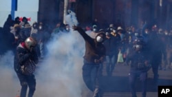 Un cultivador de coca arroja una lata de gas lacrimógeno disparada por la policía antidisturbios, durante enfrentamientos cerca del mercado de coca en La Paz, Bolivia, el 29 de septiembre de 2021. 
