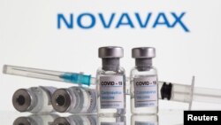 Botol berlabel "Covid-19 Coronavirus Vaccine" dan jarum suntik terlihat di depan logo Novavax, 9 Februari 2021. (Foto: REUTERS/Dado Ruvic)