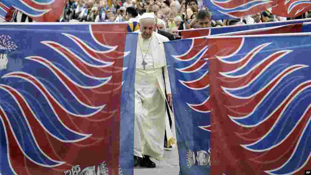 Le pape François est encadré par des drapeaux traditionnels d'une délégation de fidèles de Carovigno, du Sud de l'Italie, à son arrivée à la place Saint-Pierre pour assister à l'audience générale hebdomadaire au Vatican, le 15 octobre 2014 (AP Photo / Gregorio Borgia)