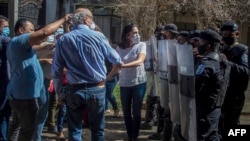 El periodista nicaragüense Carlos Fernando Chamorro, director de las publicaciones Confidencial y Esta Semana, es empujado por la policía antidisturbios frente a las oficinas de Confidencial en Managua, el 14 de diciembre de 2020.