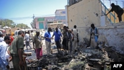 People look at the wreckage of a car bomb outside the Education Ministry in Mogadishu, April 14, 2015. AFP PHOTO / MOHAMMED ABDIWAHAB