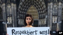 L' artiste Milo Moire tient une pancarte avec ecrit "respectez-nous !" a Cologne en Allemagne (AP Photo/Dorothee Thiesing)