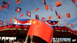 រូបឯកសារ៖ ស្ត្រី​ខ្មែរ​ម្នាក់​កាន់ទង់ជាតិ​ចិន​​ពេល​ដើរ​កាត់​ស្ពាន​មិត្តភាព​រវាង​កម្ពុជា​និង​ចិន​ ក្នុងពិធី​សម្ពោធ​ស្ពាន​នោះ​នៅ​ក្រុង​តាខ្មៅ ខេត្ត​កណ្ដាល ថ្ងៃទី ៣ ខែសីហា ឆ្នាំ២០១៥។ 
