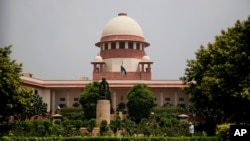 FILE - A gardener works on the lawns of the Supreme Court in New Delhi, Aug. 22, 2017. The court has agreed to hear petitions seeking legal recognition of same-sex marriages, raising hopes of securing another significant right for the country’s LGBTQ community.
