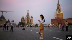 FILE - A young woman checks her smartphone at Red Square in Moscow, Russia, July 25, 2016. Russians may haver their access to Facebook blocked if the social media giant does not start storing Russian user data locally.