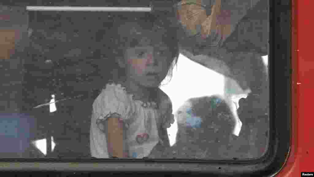 A child looks out of a train window as people who have fled from fighting in the eastern regions of Ukraine arrive at a railway station in Krasnoyarsk, Russia, on their way to a temporary accommodation in local cities and settlements in Siberia, Sept. 1,