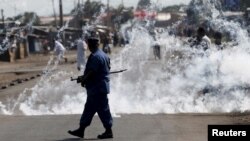 FILE - A policeman walks away after throwing a teargas canister during a protest against Burundi President Pierre Nkurunziza and his bid for a third term in Bujumbura, Burundi, June 2, 2015.