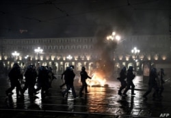 Policías cerca de un fuego encendido por manifestantes en una plaza de Turín, Italia.