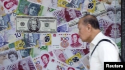 行人走过印有美金、人民币及欧元的广告牌