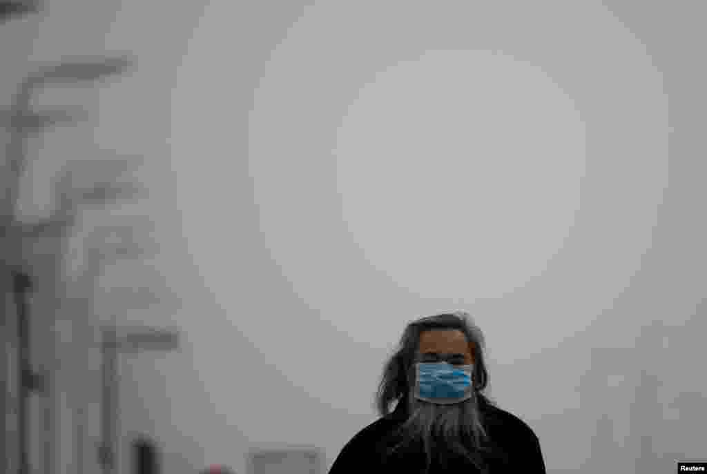 A man wearing a mask makes his way amid thick haze in Beijing, Feb. 25, 2014. 