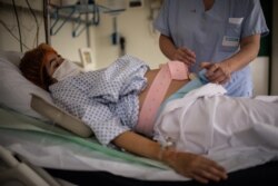Seorang perawat tengah membantu ibu hamil yang terpapar COVID-19 di Paris, Prancis, 17 November 2020. (Martin BUREAU / AFP)