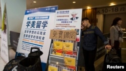 资料照片：在香港亚洲国际博览馆，一名来自中国的学生在参加完SAT考试后，在海外教育广告横幅后用手机通话。(2013年11月2日)