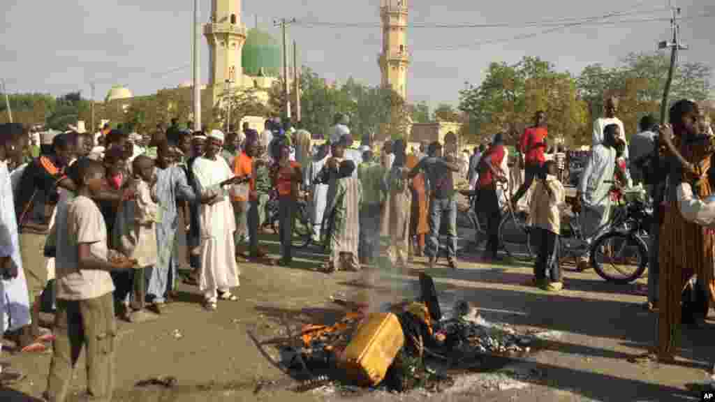 Mutane sun taru su na kallo a inda bam ya tashi a babban Masallacin Jumma'a na Kano, Jumma'a 28 Nuwamba, 2014. Mutane da yawa sun rasa rayukansu, kuma jami'ai suka ce watakila yawan wadanda zasu hallaka zai karu.