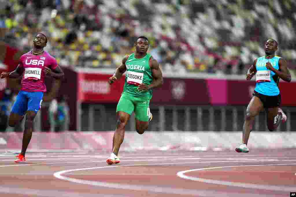 Enoch Adegoke, of Nigeria, center, wins a heat in the men's 100-meter run at the 2020 Summer Olympics, Saturday, July 31, 2021, in Tokyo. (AP Photo/Martin Meissner)