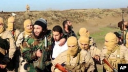 An image from Raqqa Media Center of the Islamic State group, which has been authenticated based on its contents and other AP reporting, shows Islamic State fighters with what is believed to be a captured pilot, center, in a white shirt, in Raqqa, Syria, Dec. 24, 2014.