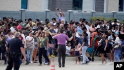 La gente se reúne frente a un centro comercial después de un tiroteo el sábado 6 de mayo de 2023 en Allen, Texas.