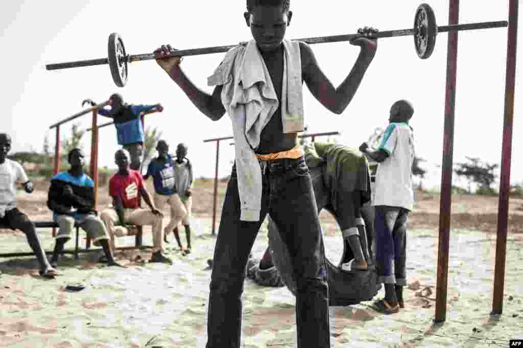 Un jeune enfant de la rue, également appelé "Talibe", joue à soulever des poids en zone de quarantaine, dans un refuge pour enfants de rue nouvellement arrivés à l'extérieur de Dakar, le 10 avril 2020.