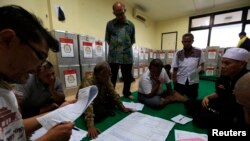Election commission official Dedi Saidi, left, reads a document stating the number of votes collected in ballot boxes, at Bendungan Hilir, Jakarta, Indonesia, July 10, 2014. 