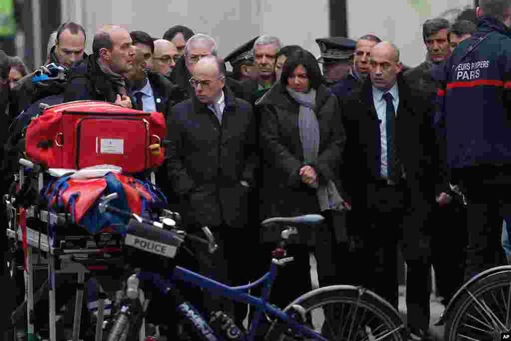 French Interior Minister Bernard Cazeneuve, center left, and Paris Mayor Anne Hidalgo, center right, arrive at the French satirical newspaper Charlie Hebdo's office, in Paris, Jan. 7, 2015.