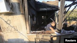 An Israeli police officer inspects a house that was badly damaged from a suspected attack by Jewish extremists on two houses at Kafr Duma village near the West Bank city of Nablus July 31, 2015.