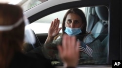In this Friday, June 26, 2020 photo, U.S. District Judge Laurie Michelson, left, administers the Aath of Citizenship to Hala Baqtar during a drive-thru naturalization service in a parking structure at the U.S. Citizenship and Immigration Services headquar