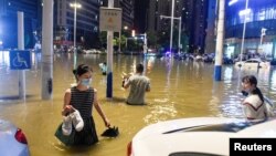 中国安徽合肥的民众在被洪水淹没的街道上过马路。（2020年6月27日）