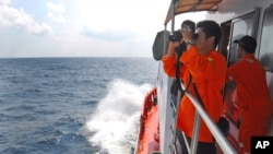 A member of Indonesian National Search and Rescue Agency (BASARNAS) uses a binocular to scan the horizon during a search operation for the missing Malaysia Airlines Boeing 777 conducted on the waters of the Strait of Malacca off Sumatra island, Indonesia,