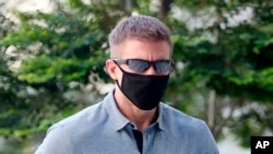 The American pilot Brian Dugan Yeargan, wearing a face mask and sunglasses, walks outside the Singapore State Court where he has been jailed for four weeks for breaching a quarantine order.