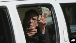 EgyptAir plane hijacking suspect Seif Eddin Mustafa flashes the victory sign as he leaves a court in a police car after a remand hearing as authorities investigate him on charges including hijacking, illegal possession of explosives and abduction in the Cypriot coastal town of Larnaca Wednesday, March 30, 2016. 
