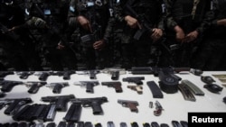 Elementos de la Policía Militar de Orden Público hacen guardia, al presentar armas y cargadores incautados en el penal de Támara, luego de que las Fuerzas Armadas de Honduras tomaran el control de los penales a nivel nacional como parte del operativo "Fe y Esperanza", en las afueras de Tegucigalpa, Honduras 26 de junio de 2023.