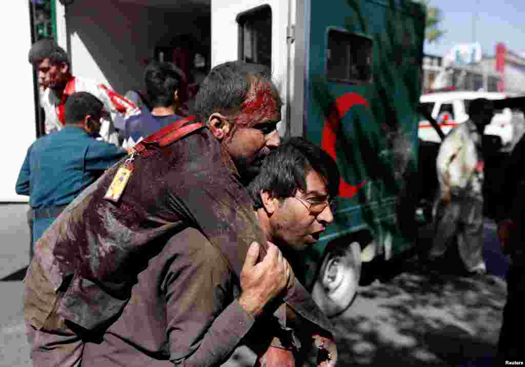An Afghan man carries an injured man to a hospital after a blast in Kabul, Afghanistan May 31, 2017.