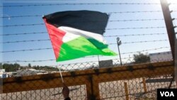 Seorang warga Tepi Barat mengibarkan bendera Palestina di pos pemeriksaan Beituniya, menunggu pembebasan 550 tahanan Palestina (18/12).