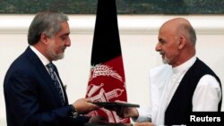 Calon presiden Afghanistan Abdullah Abdullah (kiri) dan Ashraf Ghani bertukar perjanjian yang ditandatangani untuk pembagian kekuasaan di Kabul, 21 September 2014. 