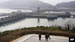North Korean men walk with the West Sea Barrage in the background in Nampo, North Korea, Feb. 2, 2019.