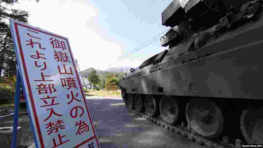 A military vehicle prepares to head to rescue climbers on Mount Ontake, background, in Otaki Village, Nagano prefecture, central Japan, Sept. 28, 2014.