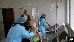 FILE - A girl, center, suspected of being infected with cholera, is treated at a hospital in Sanaa, Yemen, Sept. 9, 2019.