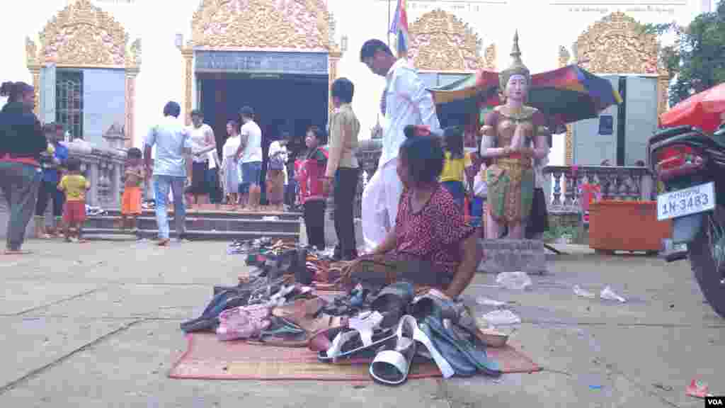 ស្រ្តីម្នាក់អង្គុយយាមស្បែកជើងរបស់ពុទ្ធសាសនិក នៅវត្តសុវណ្ណគីរីរតនៈភ្នំប្រុស (ហៅវត្តភ្នំប្រុស) ក្នុងស្រុកកំពង់សៀម ខេត្តកំពង់ចាម នៅថ្ងៃភ្ជុំបិណ្ឌ កាលពីថ្ងៃទី០១ ខែតុលា ឆ្នាំ២០១៦។ (ប៊ុន ប៉េងហ៊ុយ/VOA)