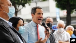 Flanqueado por colegas, el líder opositor venezolano Juan Guaidó habla durante una conferencia de prensa, un día después de las elecciones parlamentarias, en Caracas, el 7 de diciembre de 2020.