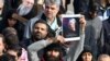 Seorang pria memegang foto Mayjen Qasem Soleimani yang tewas akibat serangan AS, dalam aksi protes di Teheran, 3 Januari 2020. 