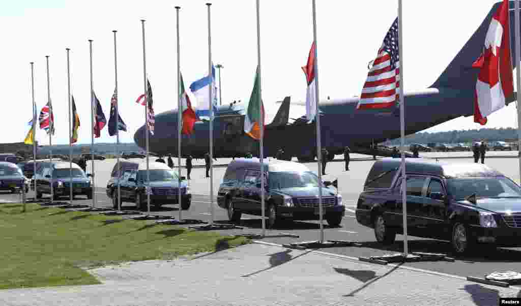 The convoy of hearses with the remains of the victims of Malaysia Airlines MH17 drives past international flags as it leaves Eindhoven airport to a military base in Hilversum, July 23, 2014.