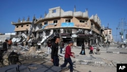 Palestinos pasan junto a edificios destruidos por un bombardeo israelí en el campo de refugiados de Nusseirat, en la Franja de Gaza, el 16 de enero, mientras la situación se agrava. 