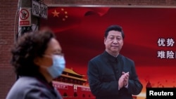 资料照：一名戴口罩妇女从习近平画像前走过。