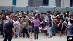 ARCHIVO - Personas se reúnen frente a un centro comercial después de un tiroteo masivo donde murieron 8 personas, el 6 de mayo de 2023 en Allen, EEUU.