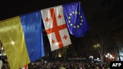 Демонстранти йдуть біля прапорів України, Грузії та Європи під час акції протесту проти рішення уряду відкласти переговори про вступ до ЄС до 2028 року, Тбілісі, 30 листопада 2024 року. Giorgi ARJEVANIDZE/AFP