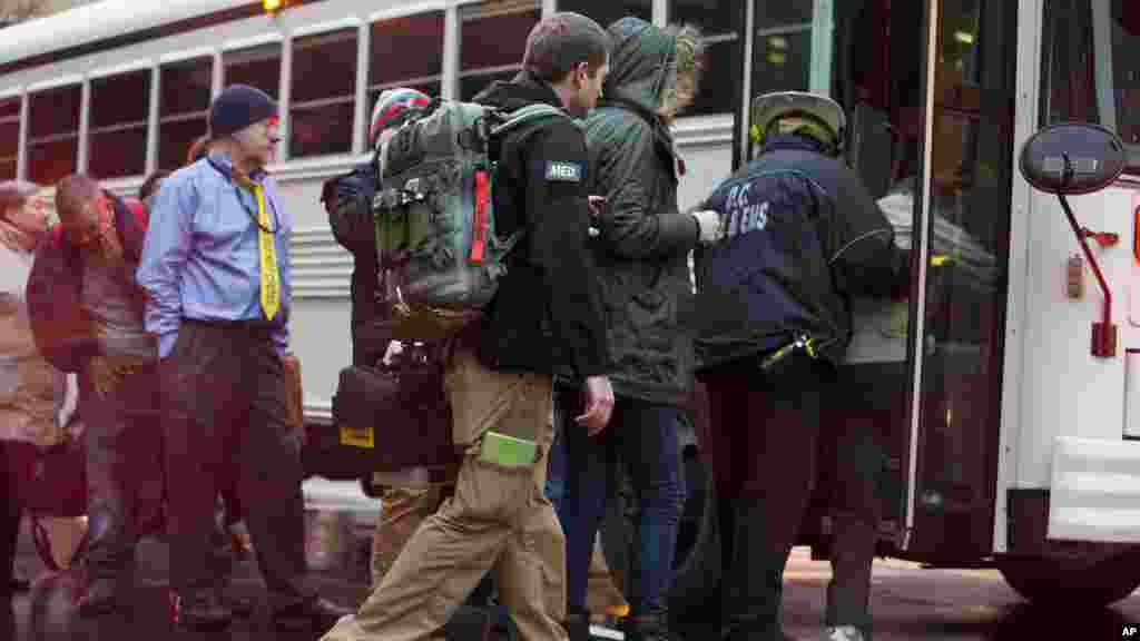 Un personnel medical du FBI, centre, aide les personnes évacuées d'un tunnel de métro enfumé à embarquer dans un bus à Washington, lundi 12 janvier, 2015.