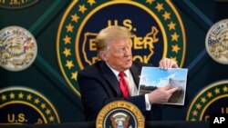 Trump muestra una fotografía en la que se puede ver una sección del muro que separa a Estados Unidos y México. Yuma, Arizona, junio 23 de 2020.