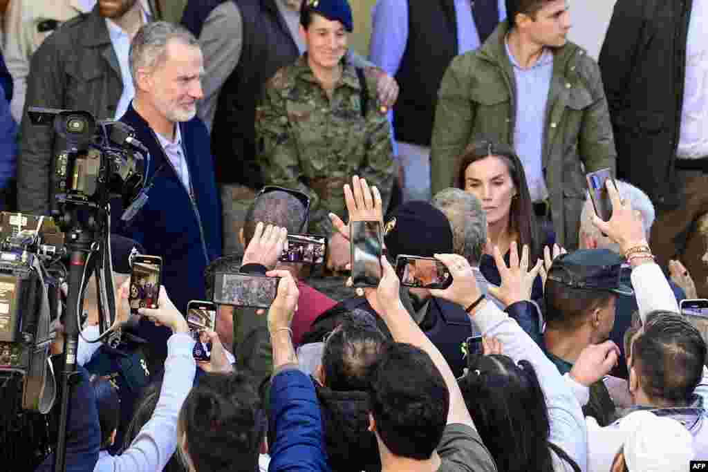 Residents take photos of Spain's King Felipe VI (L) and Queen Letizia as they visit the flood damaged town of Chiva, in the region of Valencia, eastern Spain, in the aftermath of catastrophic deadly floods. The King and Queen are returning to visit the area after they were heckled by angry residents during their first visit to the Valencia region where catastrophic floods in October left at least 226 people dead, according to officials. 