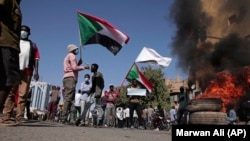 People chant slogans and burn tires during a protest to denounce the October 2021 military coup, in Khartoum, Sudan, Tuesday, Jan. 4, 2022.