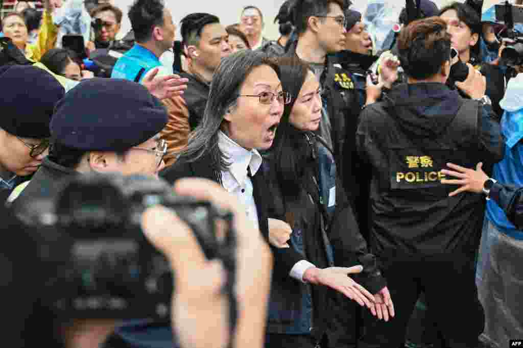 Police detain a woman (C) outside the West Kowloon Magistrates' Court in Hong Kong.Hong Kong's largest national security trial will draw to a close with dozens of the city's most prominent democracy campaigners set to be sentenced for subversion, a charge which can carry up to life imprisonment.