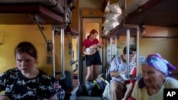 Страша сестра гойдає немовля в евакуаційному поїзді з Покровська, Донецька область, Україна, 23 серпня 2024 р. AP Photo/Evgeniy Maloletka